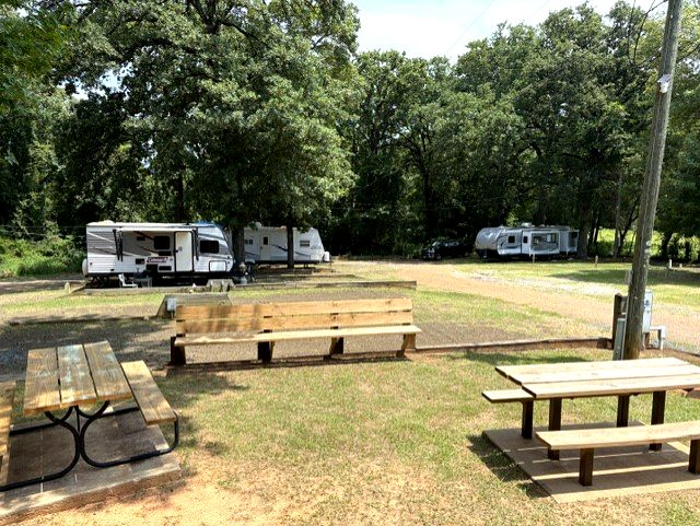 Picnic area with tables and travel trailers at Dogwood Ridge RV Park Natchitoches